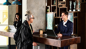 Man helping woman at reception desk