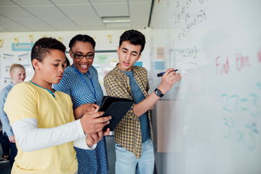 A team of people working through a problem on the white board