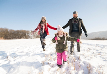 A couple and their child running in the snow