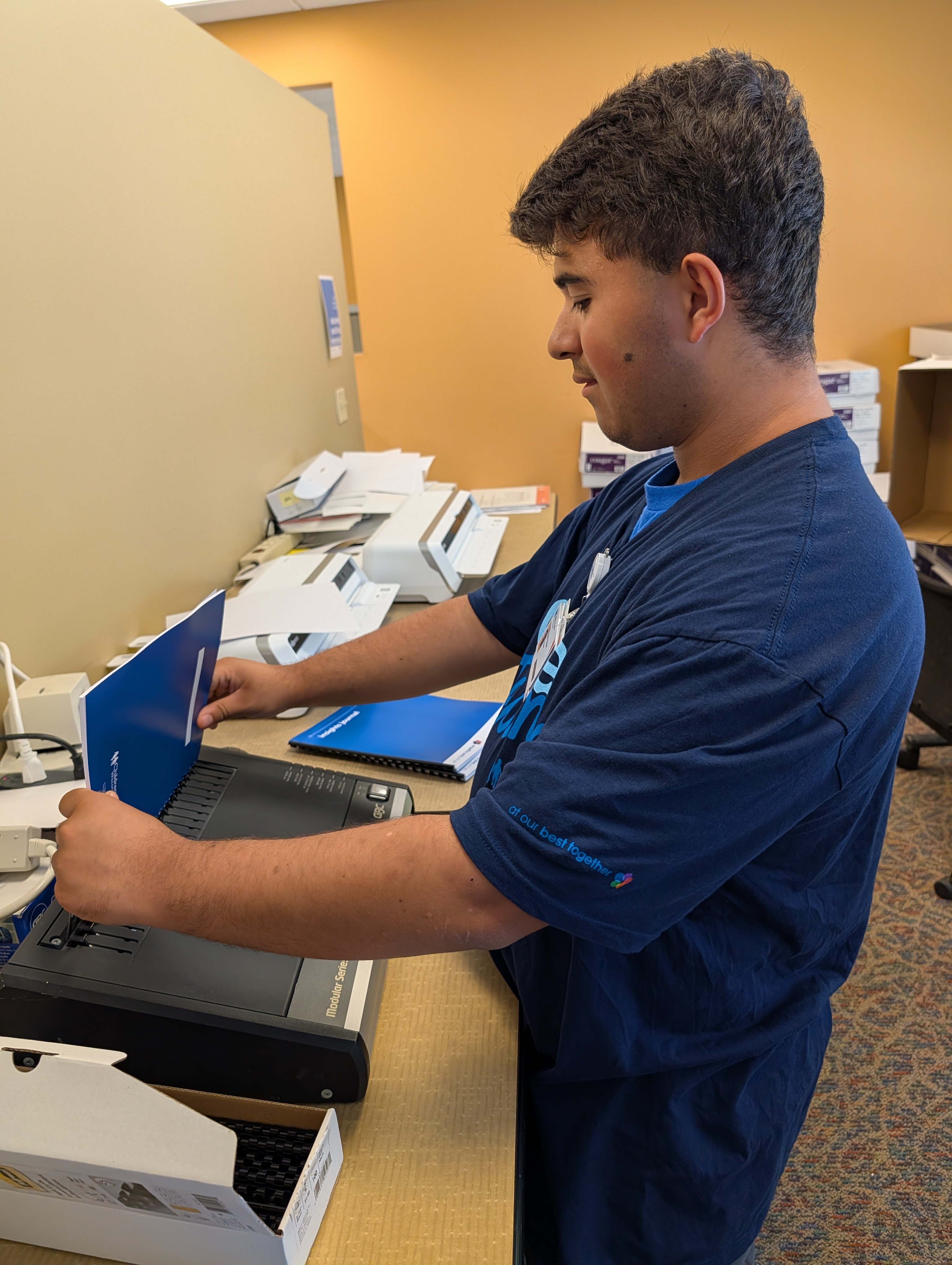 an image of Faris at a book binding machine