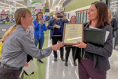 woman receiving award as people stand and watch