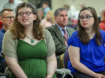 Elizabeth Wood and Isabella Theisen watch as more guests arrive as they patiently wait for the graduation ceremony to finally begin.