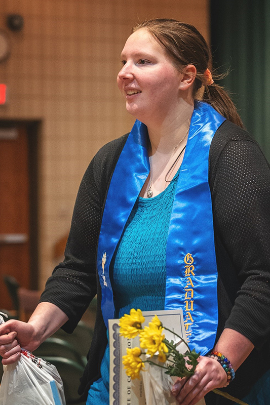 Kaylie Cavil, who is blind, reads remarks she prepared detailing her experiences during the internship. Her grandmother holds the microphone for her so Cavil can use both hands to read from her portable brail display.